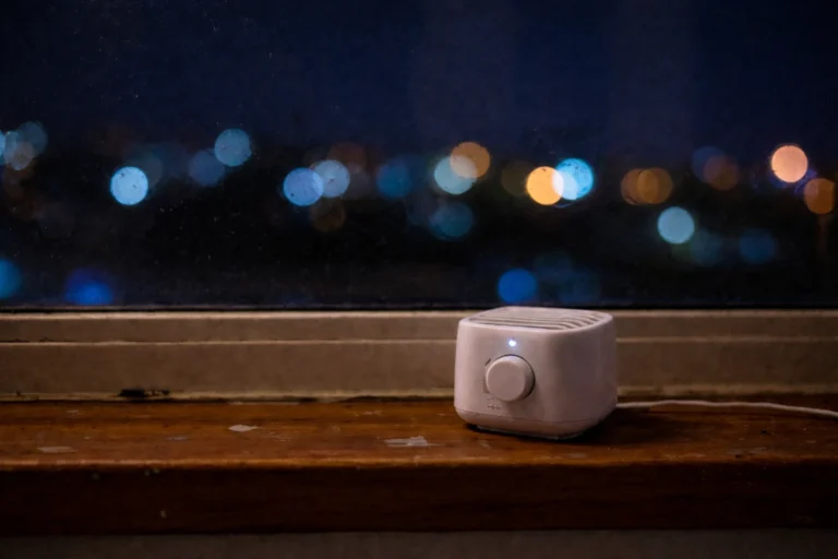 White noise machine placed near a window at night with city lights in the background