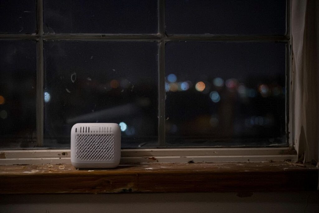 White noise machine on a windowsill at night with city lights in the background